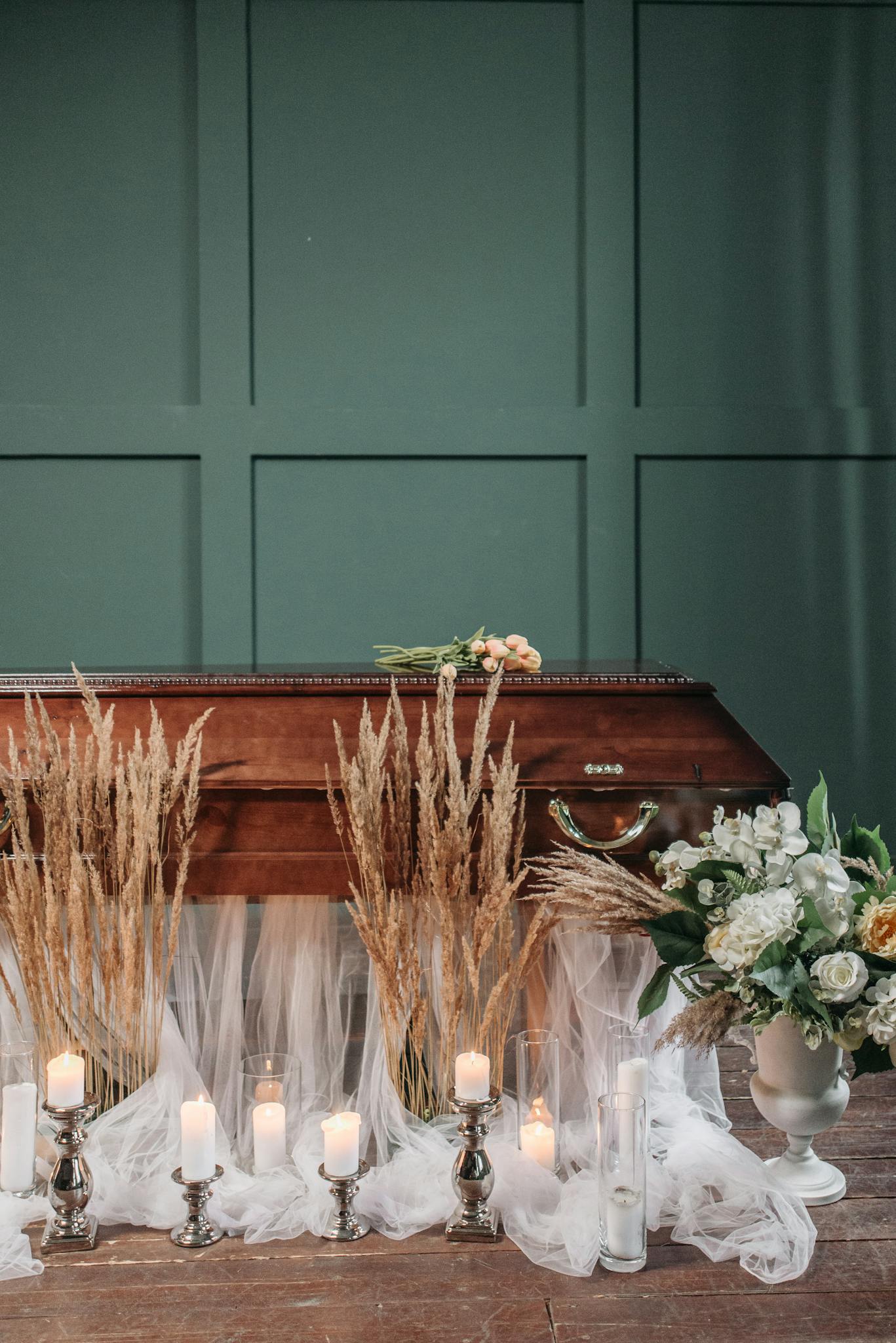 A serene funeral scene with lit candles, floral arrangements, and a coffin, creating a peaceful ambiance.