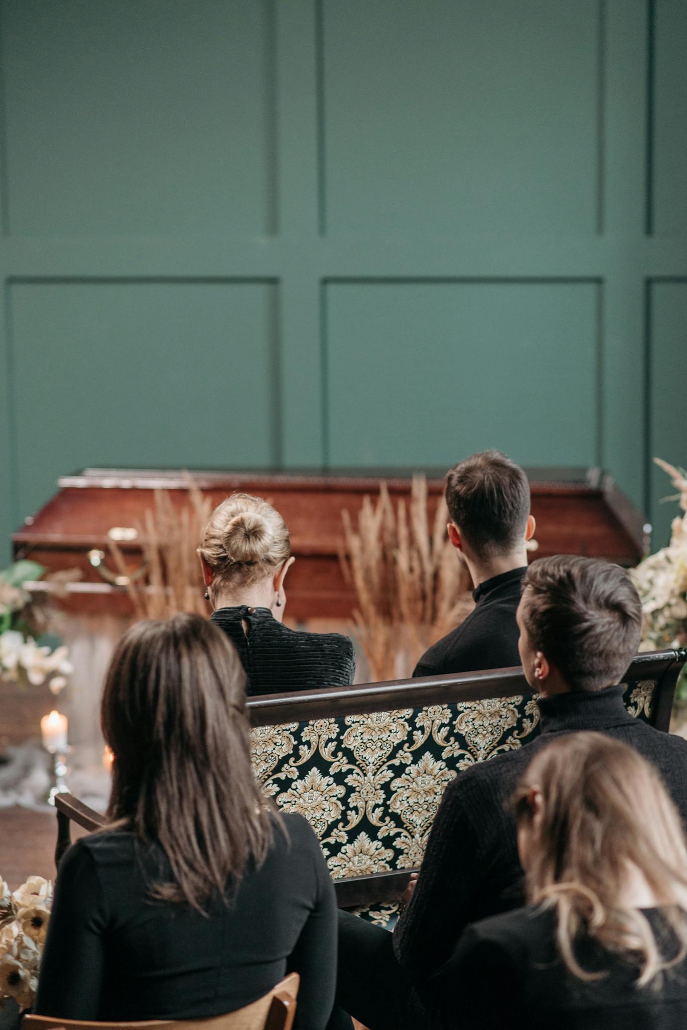 Family and friends gather indoors for a solemn funeral service.